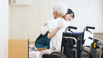 高齢者の移乗介助をするアジア人介護士