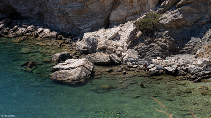 Rocky Mediterranean coastline with crystal clear water and people swimming