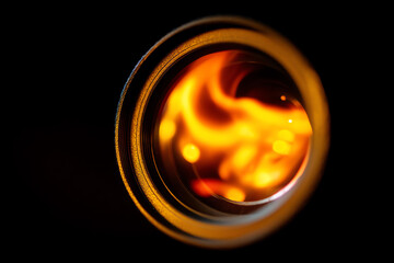 Close-up of a camera lens reflecting swirling fiery orange and yellow light patterns against a dark background