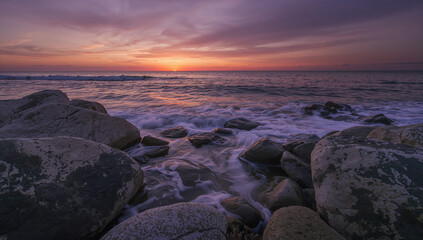 Landscape Photograph Capturing a Serene Sunset over a Rocky Ocean Shoreline