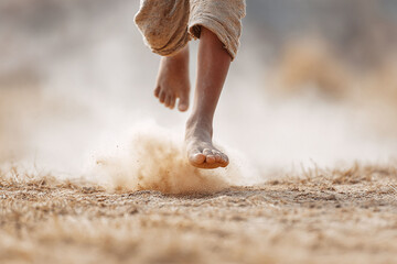 Bare feet running on dry ground, kicking up dust. Symbolizes freedom, movement, and nature. Great for travel, adventure, or childhood themes. Evokes feelings of energy.