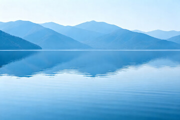 Calm lake reflecting distant mountains under a clear blue sky
