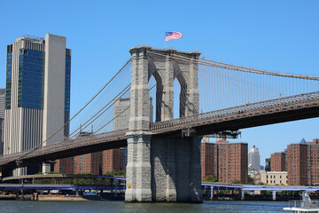 Brooklyn Bridge tower with flag and Manhattan skyscrapers NYC