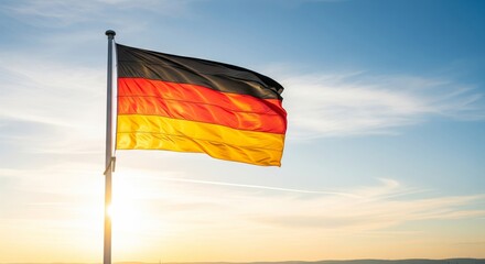 German flag waving proudly against a bright, sunny sky at sunset, symbolizing national pride and freedom.