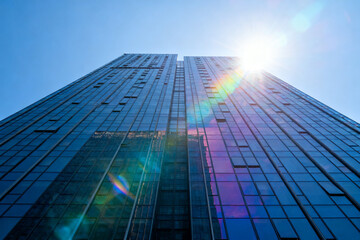 Modern glass skyscrapers under bright sunlight with lens flare effects