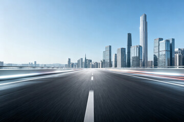 Highway leading to a modern city skyline with blurred motion effects under a clear blue sky