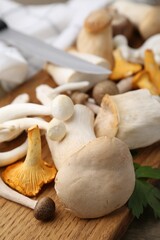 Different raw mushrooms and parsley on wooden table, closeup