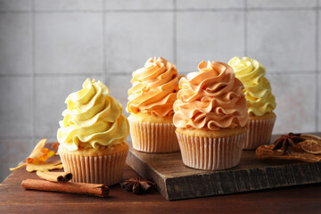 Delicious cupcakes with colorful cream and autumn decor on wooden table, closeup