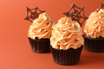 Delicious cupcakes with chocolate web on coral background, closeup with space for text. Halloween celebration
