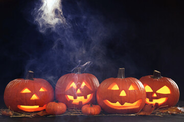 Halloween celebration. Spooky jack-o-lanterns and smoke in darkness