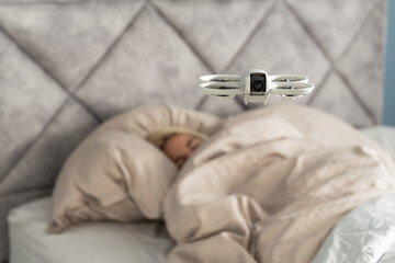 Invasion of privacy concept with a camera drone spying on a person sleeping in their bedroom at home.