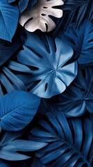 Obraz premium Dark blue monstera leaves with various textures and layers creating a tropical pattern