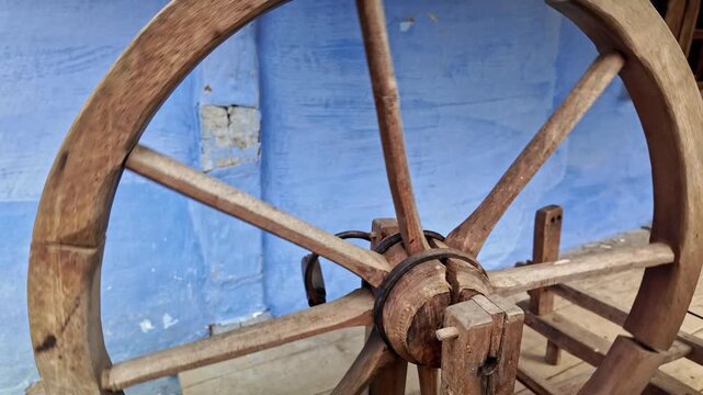 Old broken traditional wooden craft spinning wheel rocks to and fro