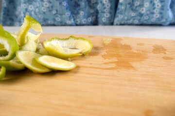 Woman putting lime peels on wooden board peeling fruit on kitchen at home. Ingredient recipe cuisine culinary. Prepare citrus natural fruit dessert, homemade fresh beverage, brazil lemonade.