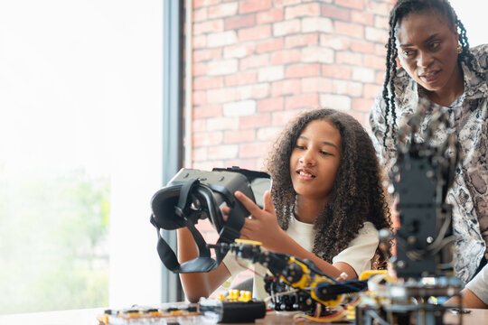 Teacher and Student Exploring Virtual Reality in a STEM Class, Young Girl Holding VR Headset While Learning Robotics and Technology, Future of Learning Immersive Technology in Education