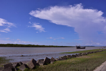 Dramatic white clouds over riverbank with fishing boats in Bangladesh