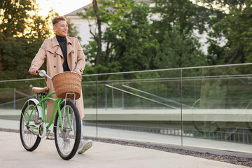 Happy man walking his bicycle on city street. Space for text