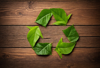 Recycling symbols made of leaves on wooden surface, eco-friendly theme
