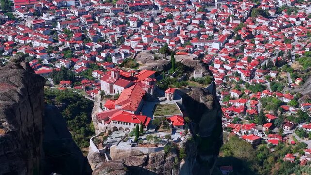 Aerial View of the Great Meteoron Monastery atop Towering Rock in Meteora and town houses of Kalambaka, Greece