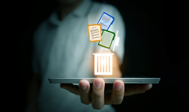 Hand holding tablet with glowing recycle bin icon, deleting colorful digital documents, symbolizing file management, data cleanup, and secure technology solutions.