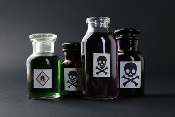 Bottles of poison with warning signs on grey background, closeup