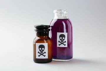 Bottles of poison with warning sign on light background