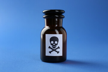 Bottle of poison with warning sign on light blue background, closeup