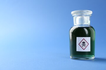 Bottle of poison with warning sign on light blue background, closeup. Space for text
