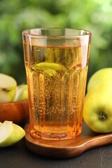Delicious cider in glass and apples on black table outdoors, closeup