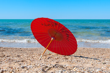 Red chinese parasol on a seashore at sunny day