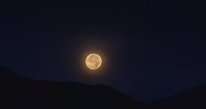 Full moon setting over dark mountains in Kotor, Montenegro, on September 7, 2025, glowing in deep night sky with soft halo and serene landscape. Time lapse