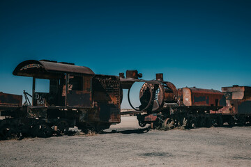 An abandoned locomotive cemetery in Uyuni. Old, rusty, forgotten trains in Bolivia. Sunny day. Blue sky.