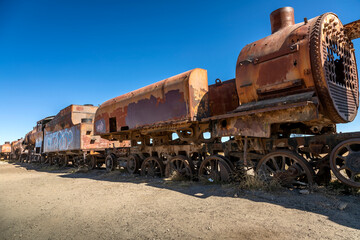 An abandoned locomotive cemetery in Uyuni. Old, rusty, forgotten trains in Bolivia. Sunny day. Blue sky.