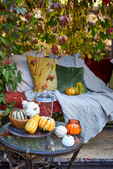 Cozy autumn still life in a garden with rustic table, pumpkins, quinces, glass jar, and warm seasonal decor. Outdoor fall atmosphere with natural colors, homely comfort, and countryside charm, perfect