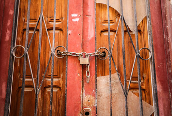 Old wooden door with wrought iron details and closed with rusty chain