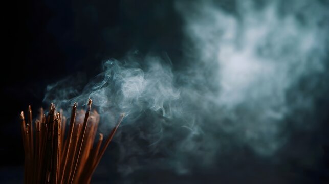 Fototapeta Burning incense sticks release wisps of smoke against a dark atmospheric background