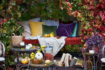 Cozy autumn still life in a garden with rustic table, pumpkins, quinces, glass jar, and warm seasonal decor. Outdoor fall atmosphere with natural colors, homely comfort, and countryside charm, perfect
