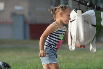 Young girl with light hair wearing a striped tank top featuring a pineapple design, standing...