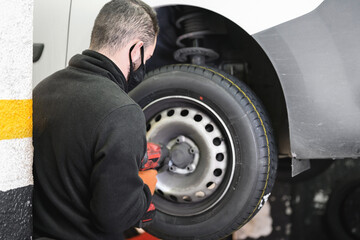  shot of an unrecognizable mechanic using an electric impact wrench to remove a car wheel. High quality photo