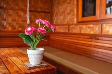 Vibrant pink flowers in a decorative pot on a rustic wooden table, creating a cozy and inviting interior ambiance