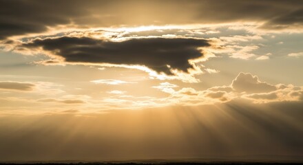 Sunbeams breaking through dramatic clouds at sunset, casting golden light across the horizon.