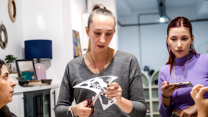 In an art studio during a group art event, a middle-aged woman artist is cutting stencil templates with scissors to shape the clay © HI Pictures