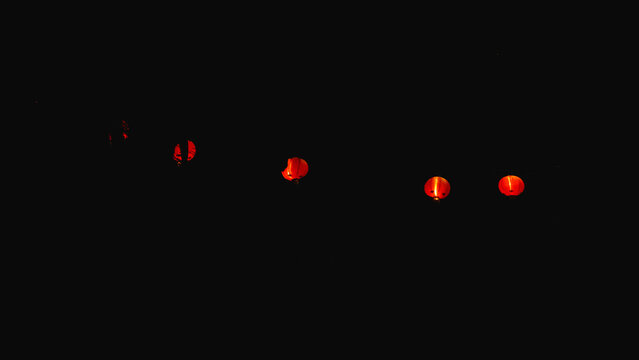 A row of traditional red Chinese lanterns glowing beautifully in the dark night, symbolizing culture, celebration, and festivity with warm and vibrant illumination.