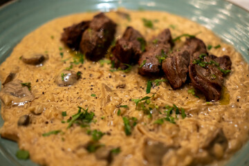 Risotto with sliced meat steak served on plate. It is a popular Italian rice dish.