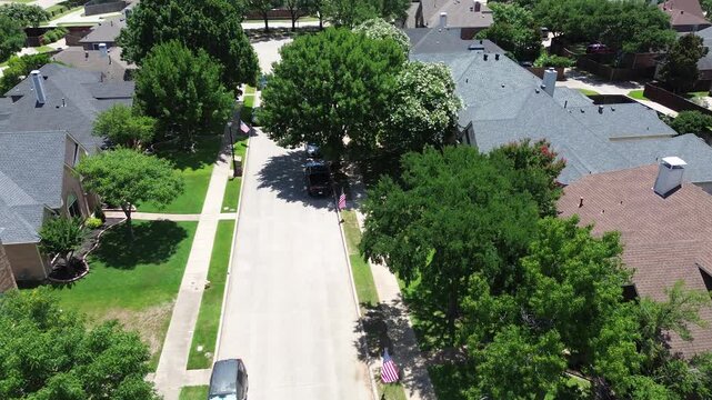 Quiet suburban street in North Coppell, Texas lined with mature trees, sidewalks, row of single-family homes featuring varied rooflines, driveways, green lawns near school zone in suburb Dallas