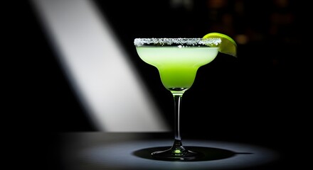 Vibrant green margarita cocktail with a salted rim and lime garnish, illuminated in a dark setting