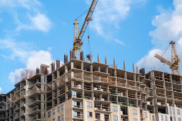 A construction site is bustling with activity as cranes lift materials and workers are busy on a high-rise building under a sunny sky. © Anat art