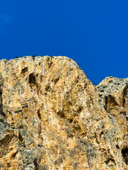 Majestic cliffs rise against a clear blue sky, showcasing the beauty of natural rock formations in a sunlit landscape during the afternoon