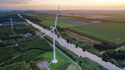 Aerial view of windmills along water canal in Netherlands. Wind farm at sunset. Alternative energy. © Todayphoto