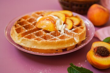 Homemade Belgian Waffles topped with fresh peaches and cream, selective focus